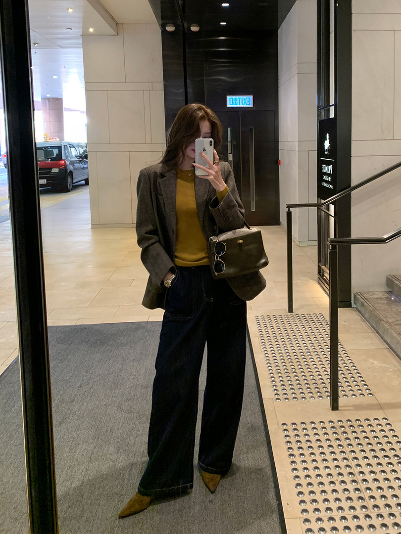 Mirror selfie of a woman wearing a blazer, wide-leg trousers, and carrying a handbag