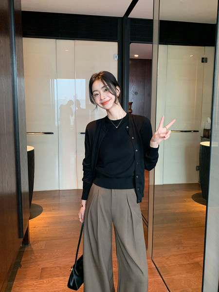 Woman wearing a black top and cardigan with wide-leg gray trousers