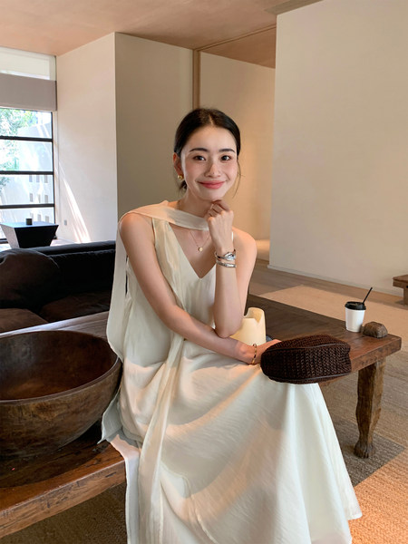 Woman modeling a cream sleeveless flowy dress indoors