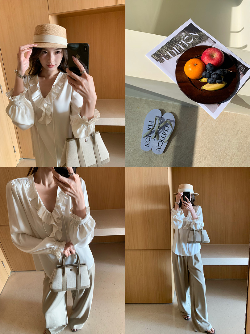 Cream ruffled blouse and wide-leg pants outfit worn with a straw hat and handbag