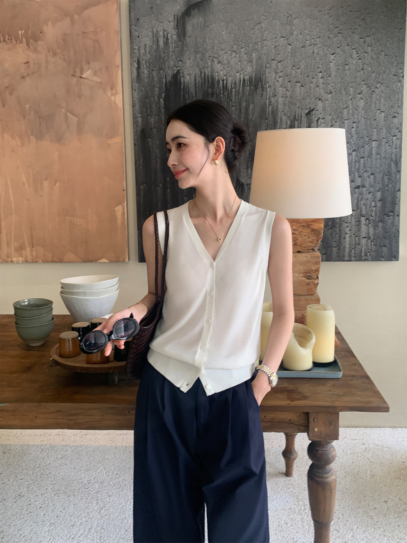 Woman wearing a white sleeveless button-front top with navy wide-leg pants