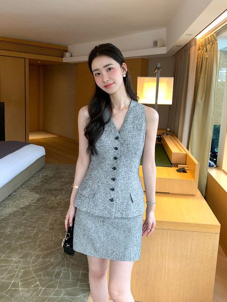 Woman wearing a gray tweed sleeveless vest and matching skirt set