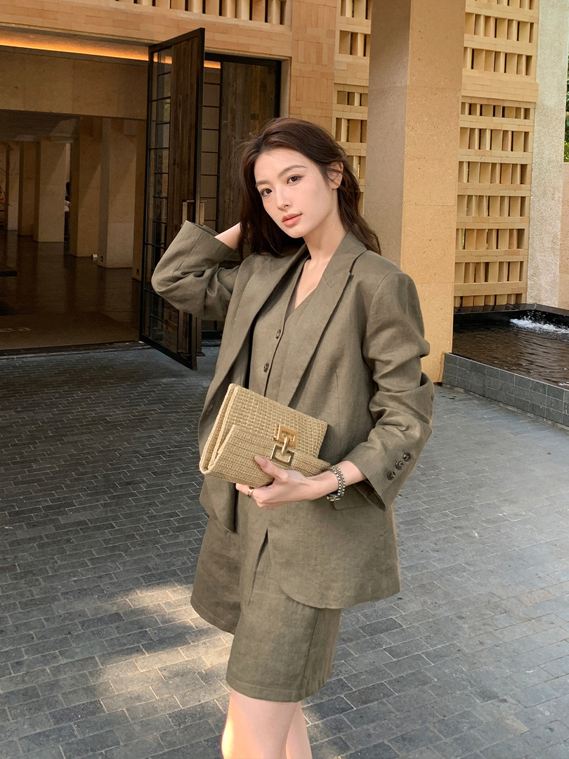Woman wearing an olive blazer and matching shorts while holding a woven clutch