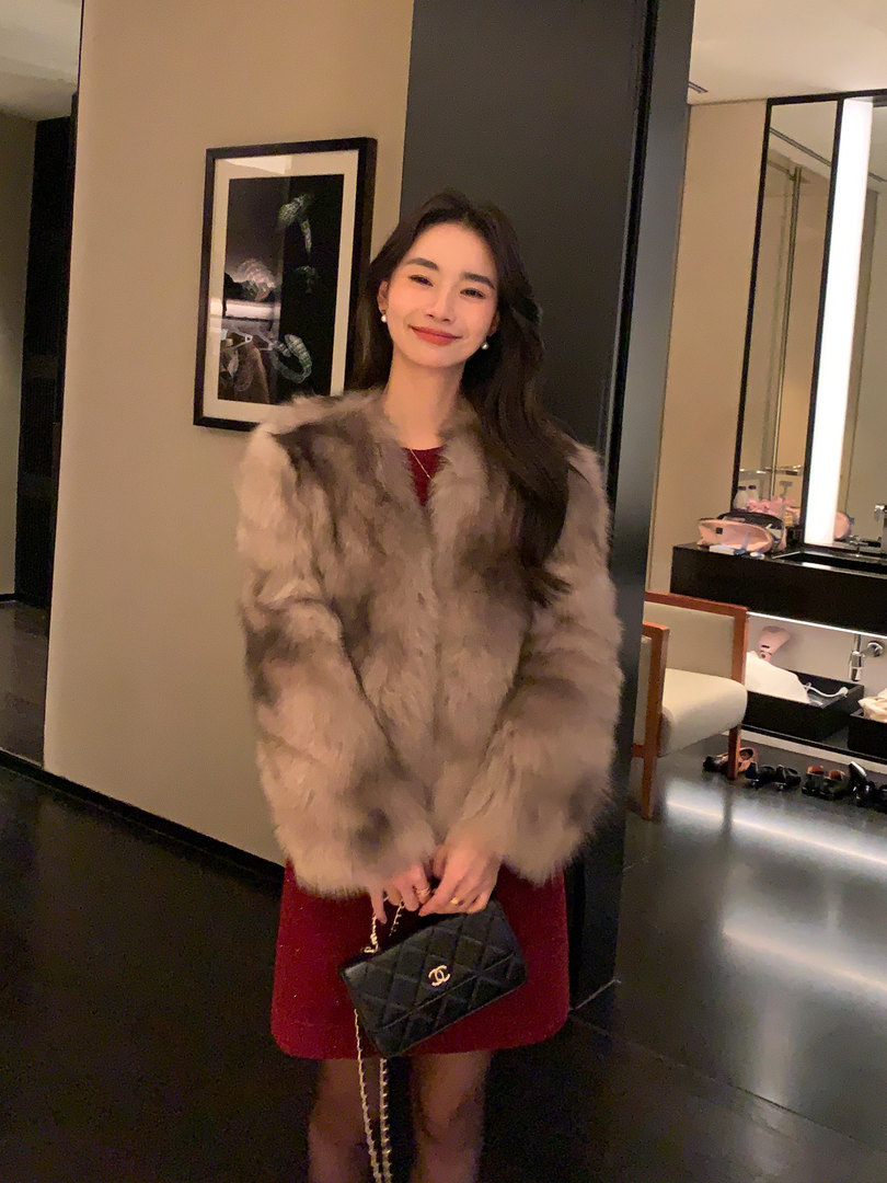 Woman wearing a gray faux fur coat and holding a black quilted handbag