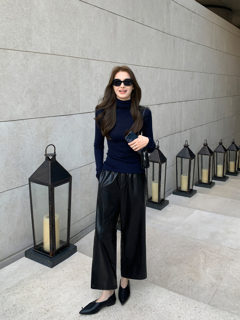 Woman wearing a navy turtleneck top with black wide-leg pants and black flats