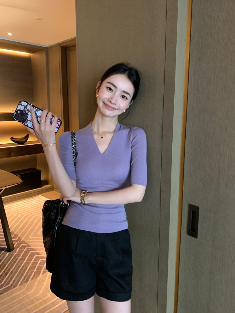 Woman wearing a lavender fitted top with black shorts in a mirror selfie
