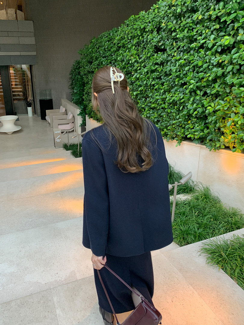 Woman wearing a navy tailored outfit with a matching jacket and skirt while carrying a handbag