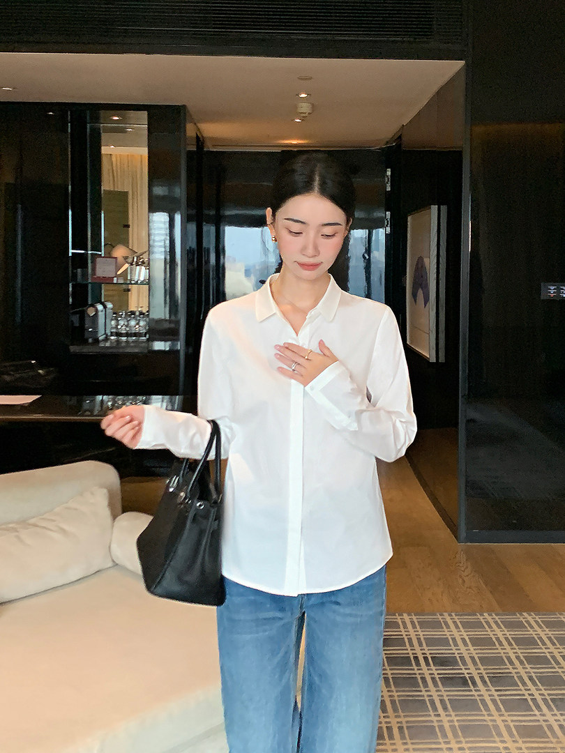 Woman wearing a white button-up shirt with blue jeans and a black tote bag