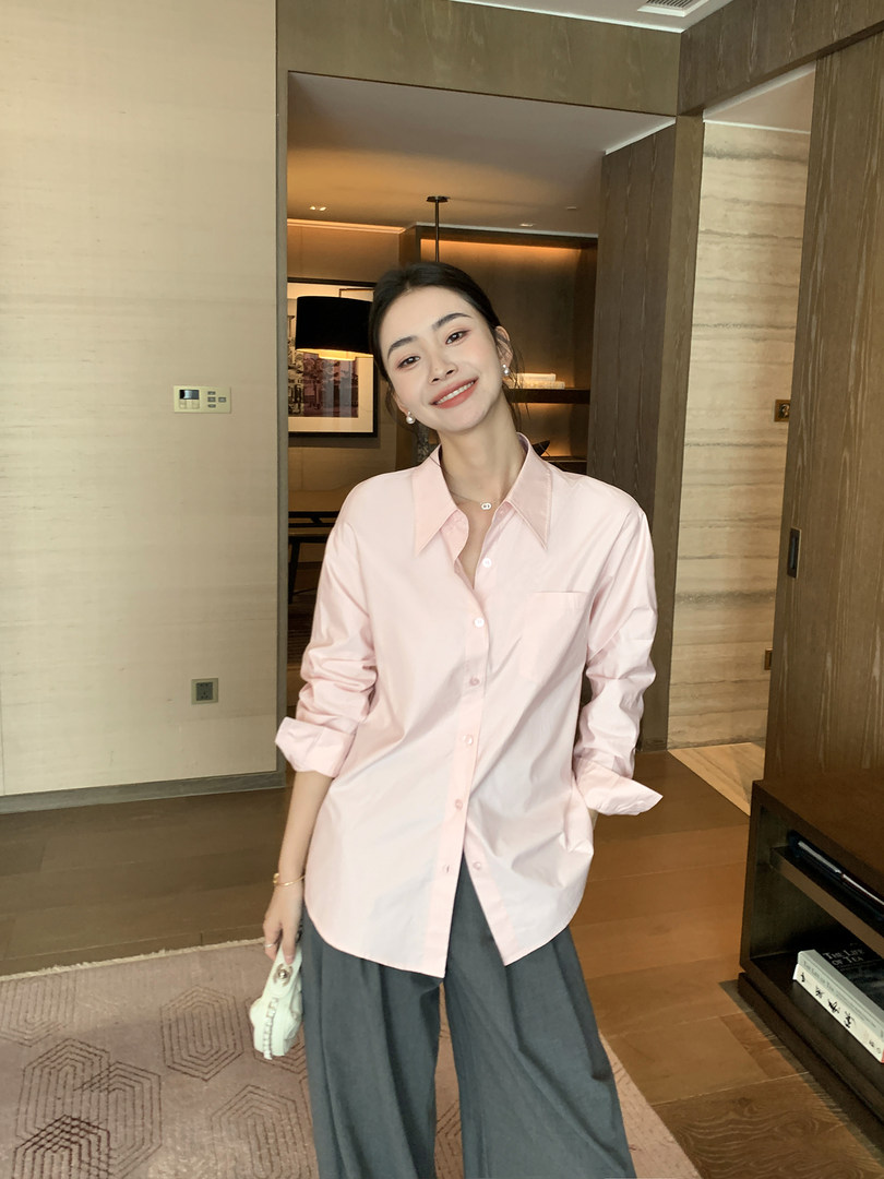 Woman wearing a light pink button-up shirt with dark wide-leg pants
