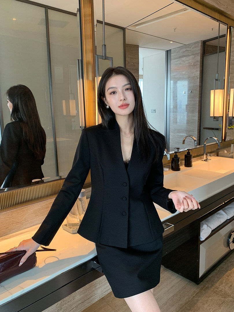 Black tailored blazer and skirt suit worn by a model in a modern interior