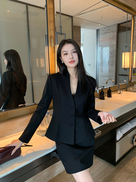 Black tailored blazer and skirt suit worn by a model in a modern interior