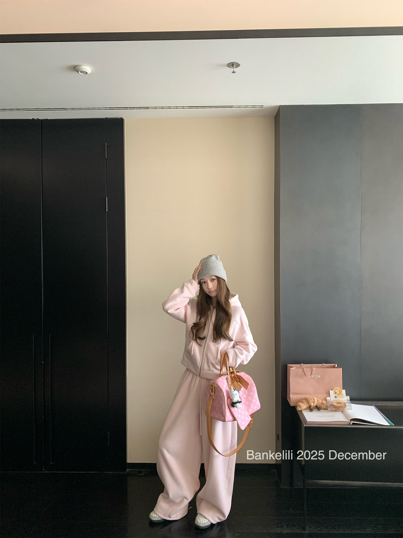 Model wearing a pink hoodie and wide-leg lounge set with a gray beanie and pink handbag