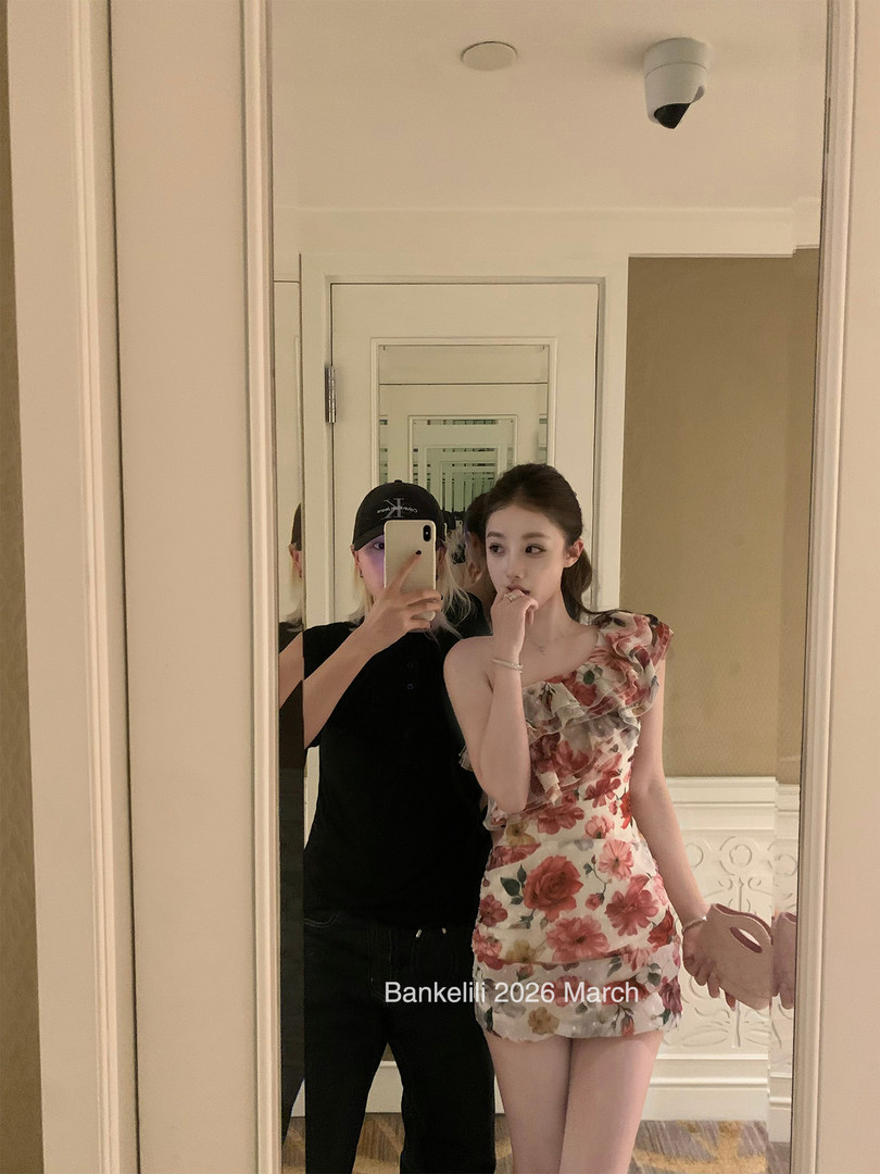 Woman wearing a floral one-shoulder mini dress in a mirror selfie