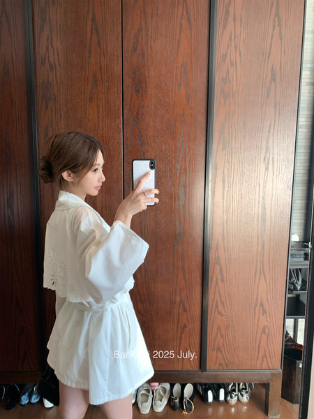Woman wearing a white robe-style dress in a mirror selfie