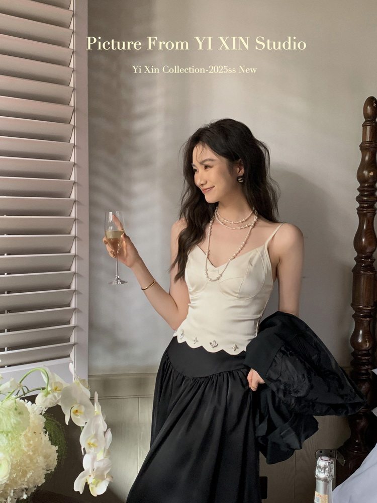 Model wearing a cream camisole top with a black skirt indoors