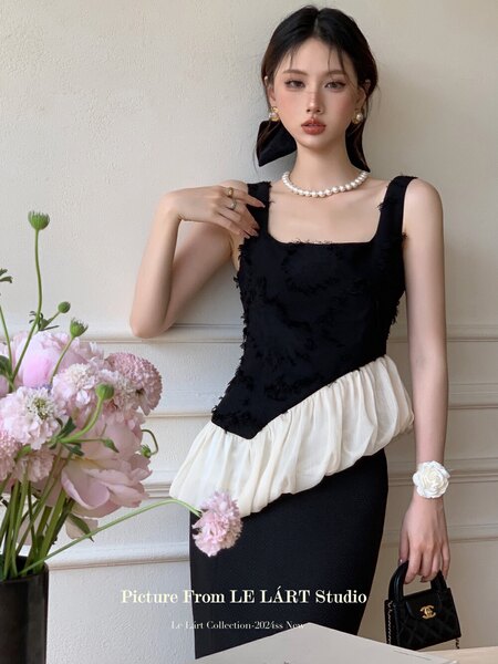 Model wearing a black and white sleeveless fitted dress with a pearl necklace and handbag