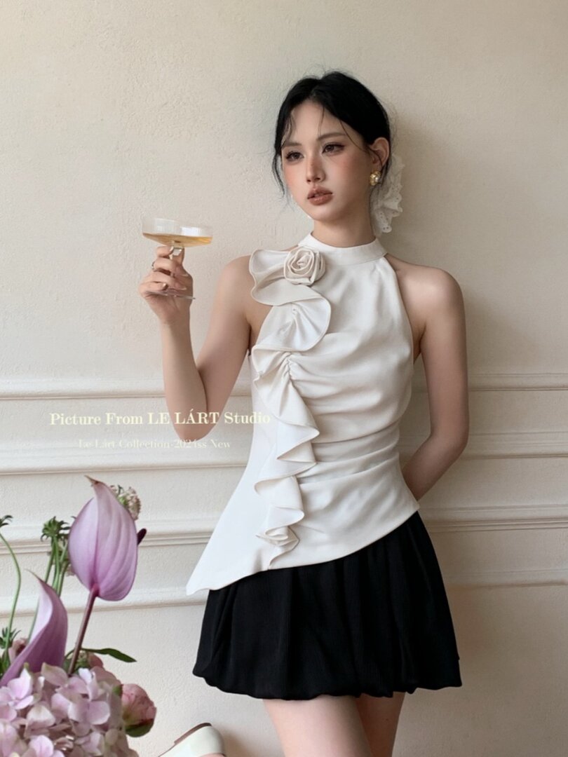 Model wearing a white ruffled halter top with a black skirt