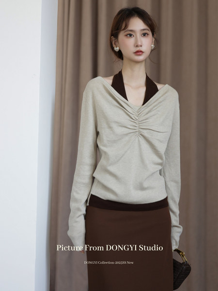 Model wearing a beige draped long-sleeve top with a brown skirt