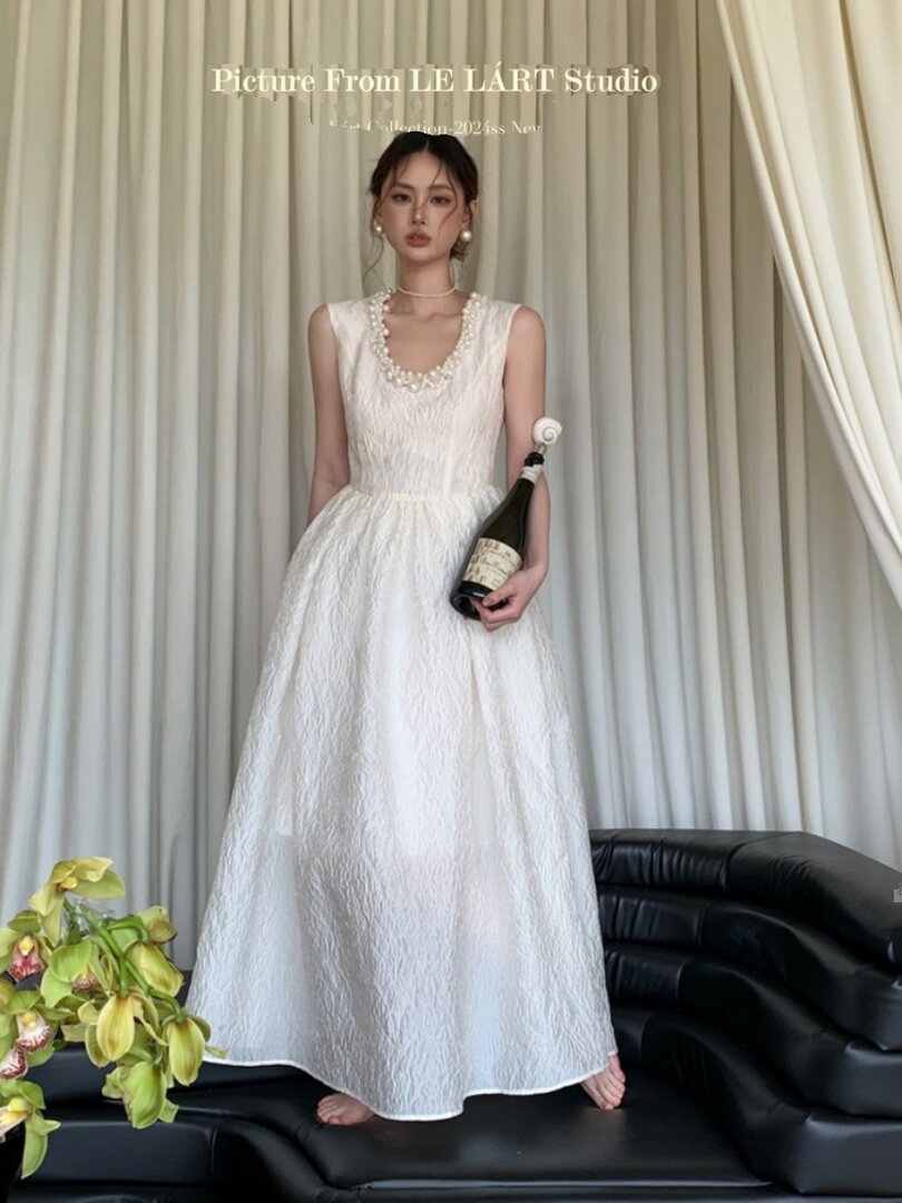 Model wearing a long white sleeveless formal dress