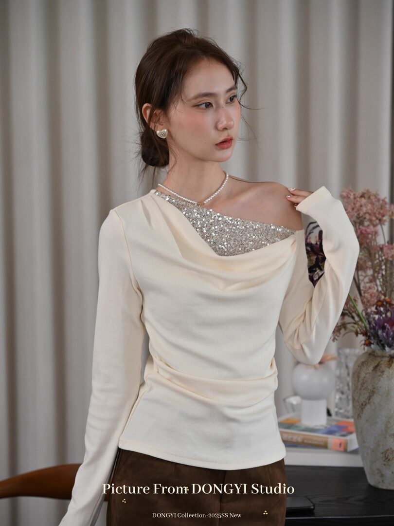 Model wearing an ivory off-shoulder embellished long-sleeve top