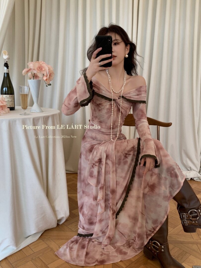 Woman wearing a pink off-shoulder maxi dress with dark trim and boots