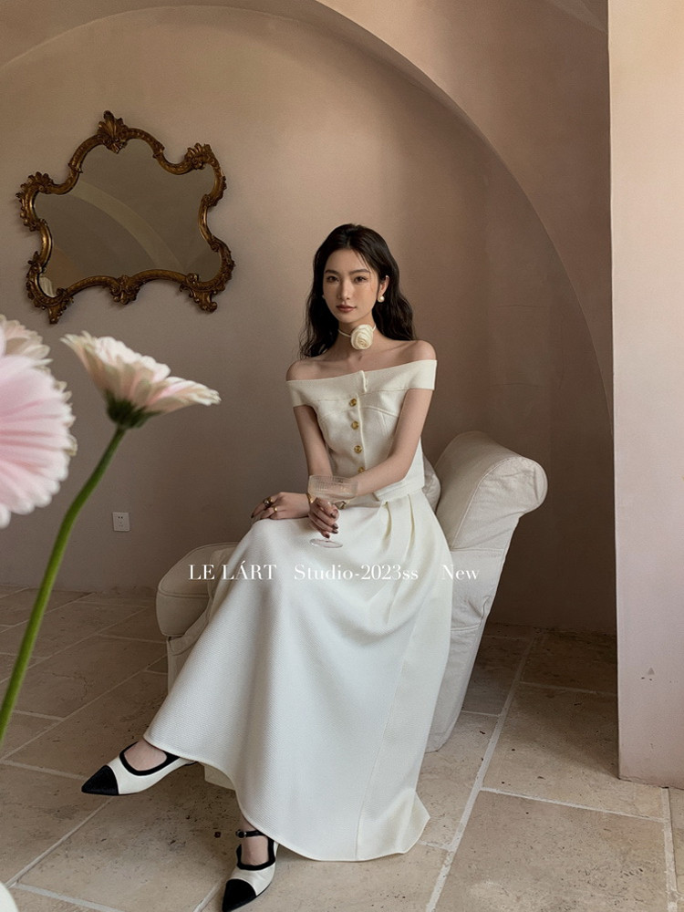 White off-shoulder long dress worn by a model in a studio setting