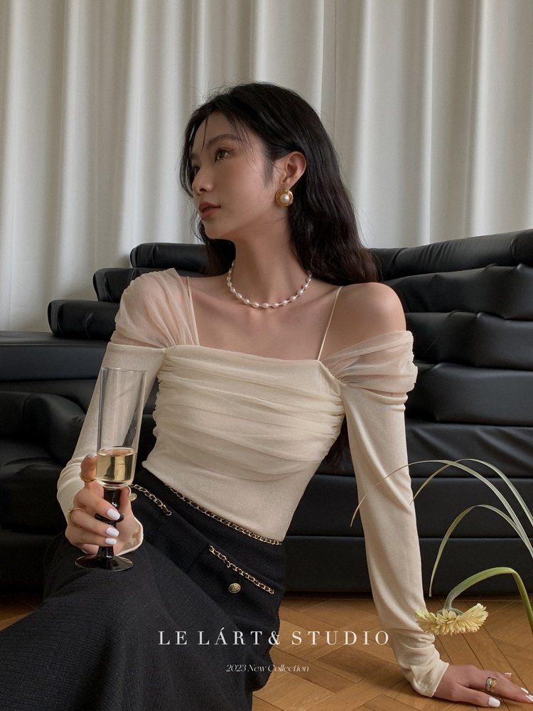 Woman wearing a cream off-shoulder ruched top with long sleeves
