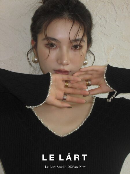 Black long-sleeve knit top with pearl trim worn by a model