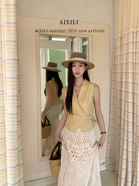 Woman wearing a yellow sleeveless wrap top and white lace skirt with a straw hat and woven bag