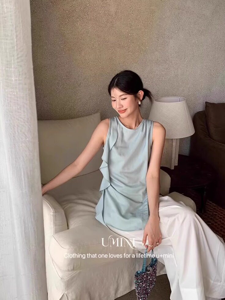 Light blue sleeveless draped top worn with white pants
