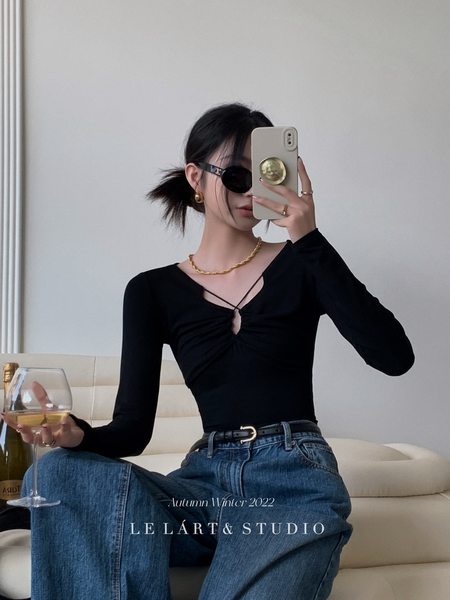 Model wearing a black long-sleeve top with blue jeans in a fashion photo