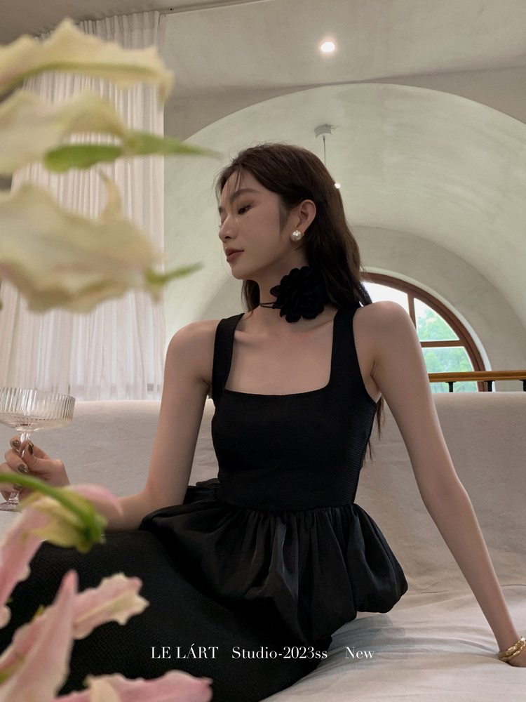 Black sleeveless dress worn by a model in an elegant indoor setting