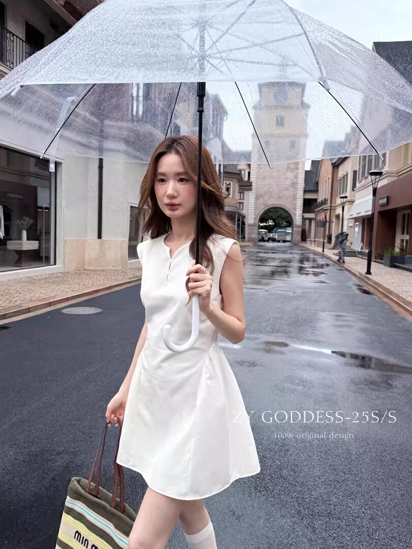 White sleeveless dress worn by a model holding a clear umbrella