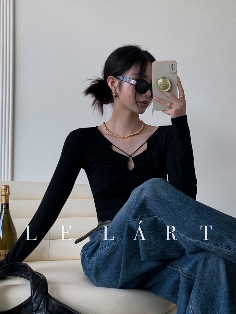 Black long-sleeve fitted top worn with blue jeans on a model