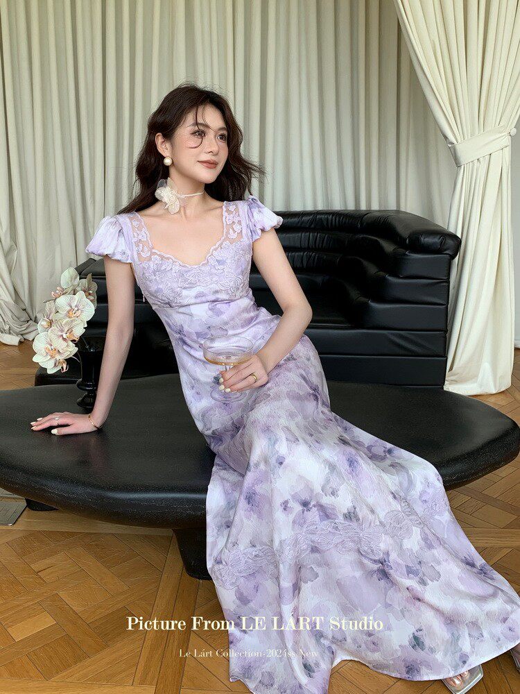 Lavender floral maxi dress worn by a model on a black sofa