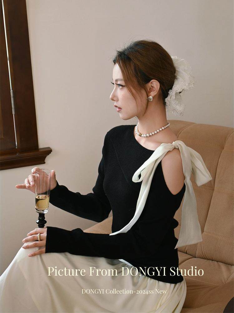 Black one-shoulder dress with a white bow detail worn by a model