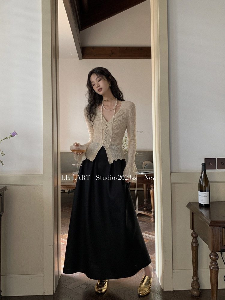 Model wearing a cream lace blouse with a black long skirt and gold shoes in a mirror photo