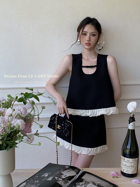 Black sleeveless mini dress with white ruffle trim worn by a model