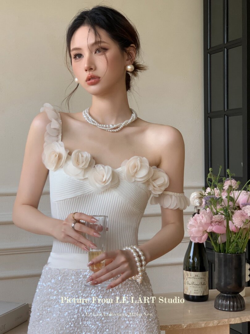 Woman wearing a white off-shoulder floral embellished dress with a sequined skirt