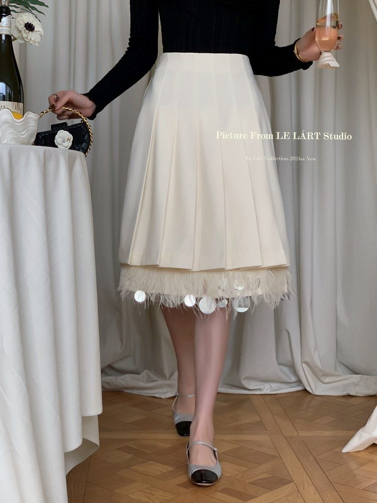Model wearing a white pleated skirt with feathered hem and black top