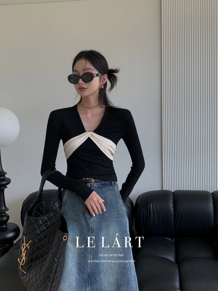 Model wearing a black long-sleeve twist-front top with a denim skirt and black handbag