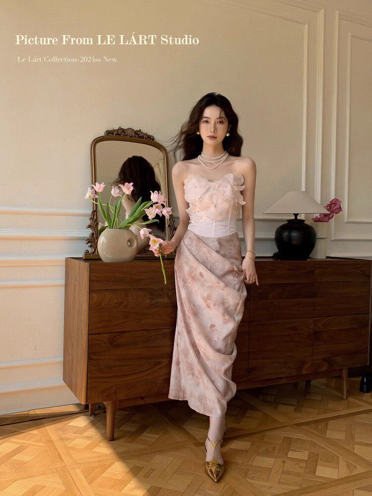Model wearing a pale pink strapless floral dress in a styled room