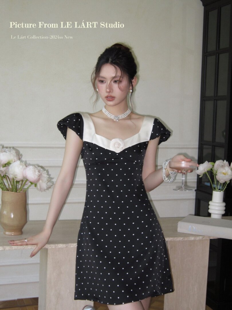 Black polka dot mini dress with white trim worn by a model