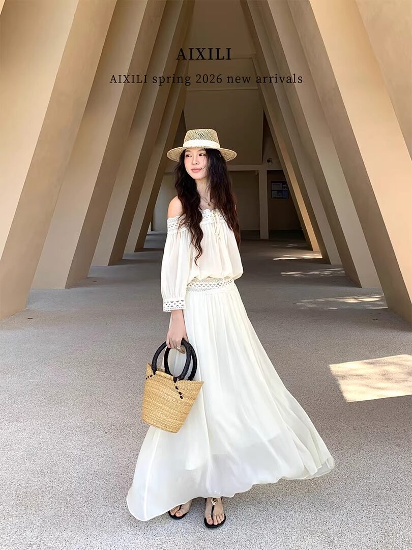 Woman wearing a white off-shoulder maxi dress with a straw hat and woven bag