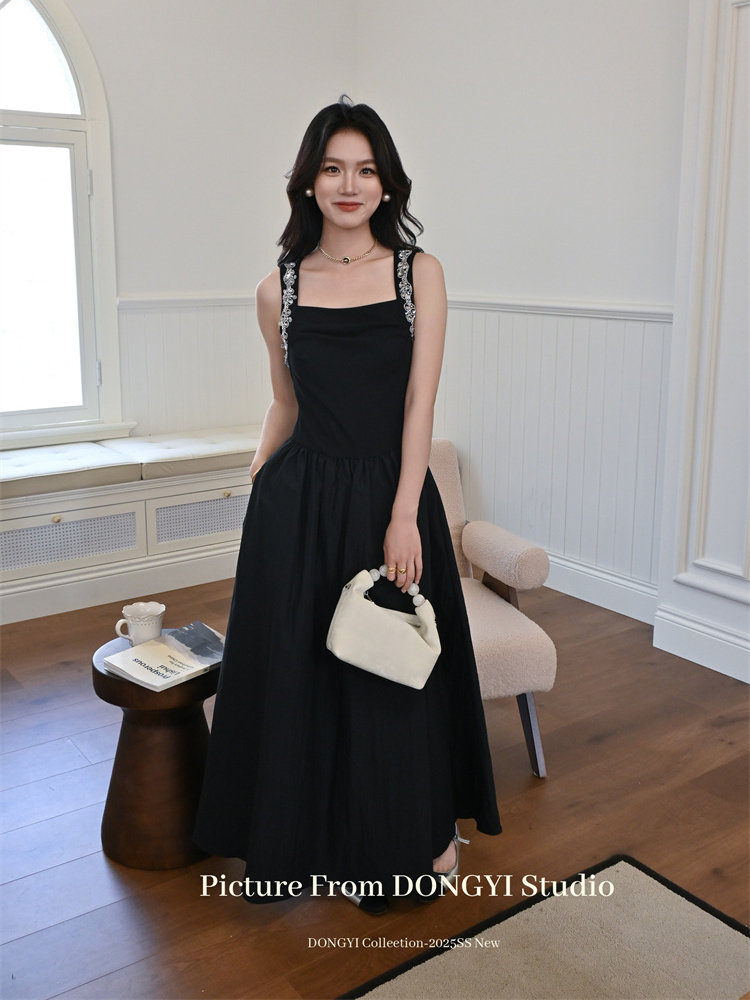 Black sleeveless maxi dress worn by a model holding a small white handbag