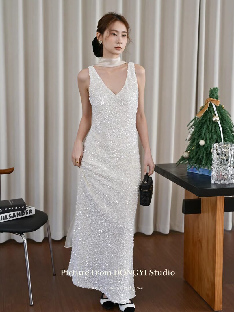 White sequined sleeveless evening gown worn by a model