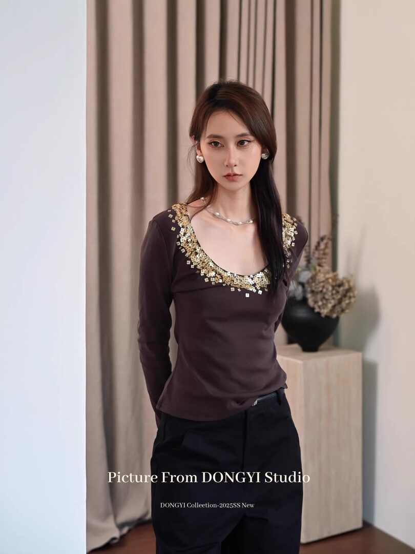 Model wearing a dark long-sleeve embellished top with a low neckline