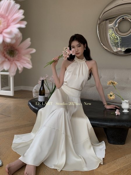 Cream halter-neck maxi dress worn by a model indoors