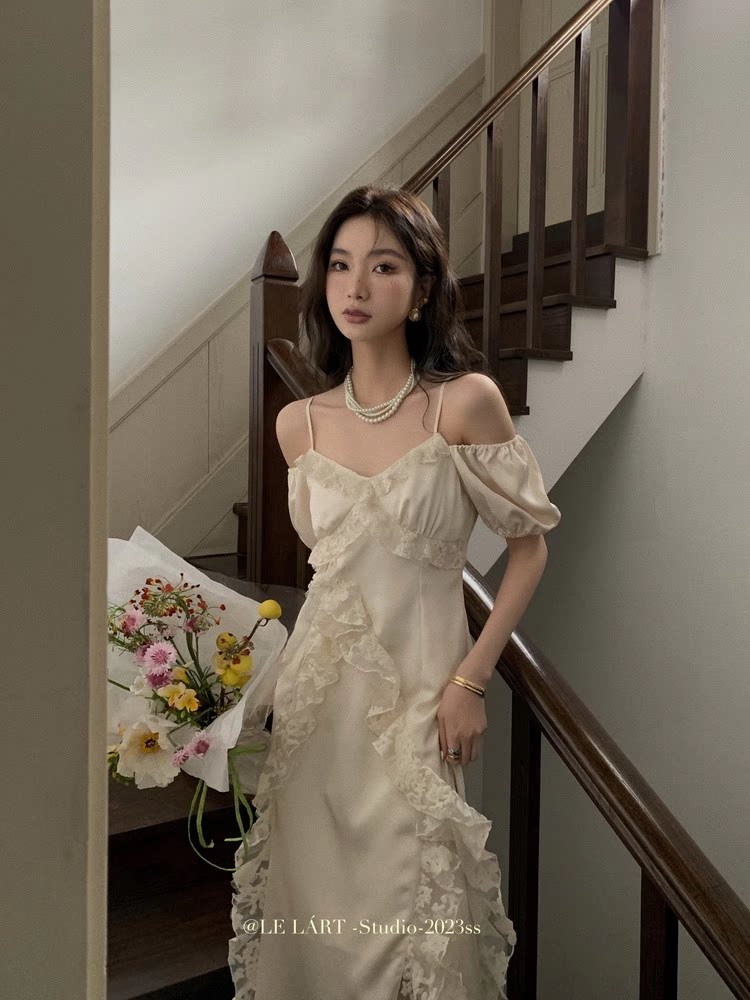 Cream off-shoulder ruffled dress worn by a model indoors