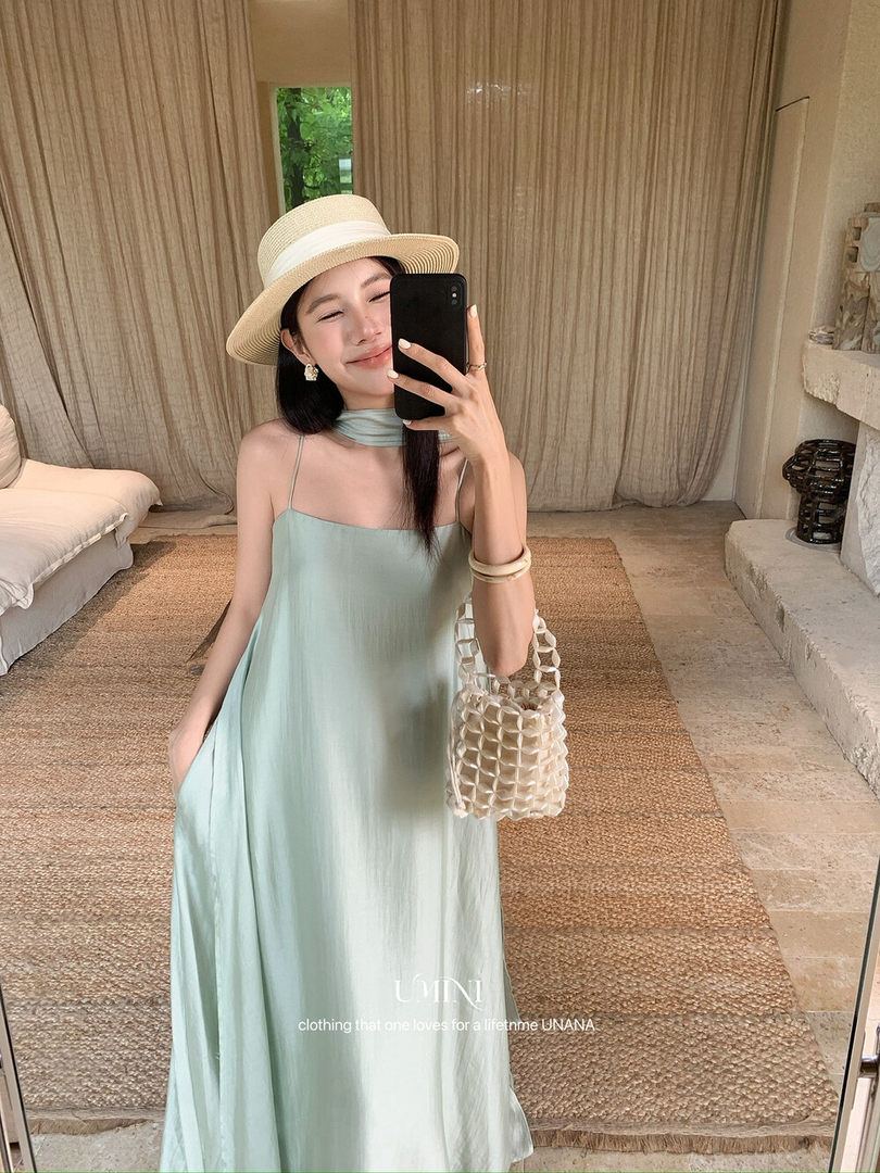 Woman wearing a mint green maxi dress with a straw hat and woven bag